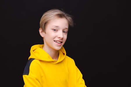 Handsome smiling young european guy teenager speechlessly looking at camera shocked by high prices, wears casual bright yellow hoodie isolated on blue backgroundの写真素材