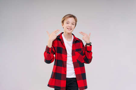 Smiling toothy funny young caucasian teenage guy in simple casual t-shirt and shirt in red cage looking at camera isolated on studio portrait against white wall background. Emotions lifestyle conceptの写真素材