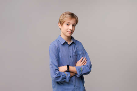 Laughing young guy in casual blue shirt posing isolated on light gray wall background, studio portrait. People lifestyle concept. Copy space for copy. Holding hands crossing, looking at the cameraの写真素材