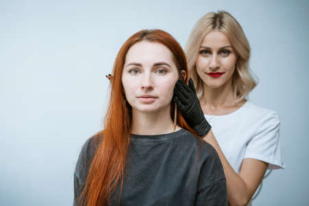 Master beautician makes markup of eyebrow tattooing, women before applying permanent makeup, permanent eye makeup and eyebrow correction procedure. Happy client girl is very satisfiedの写真素材