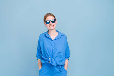 Photograph beautiful positive young woman wearing casual shirt and stylish sunglasses isolated on a...