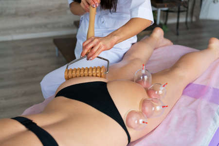 Stimulation lymphatic system with wood therapy treatment. Massage with wooden roller to eliminate liquids and cellulite. Improve circulation in the legs. Aesthetic toolsの写真素材
