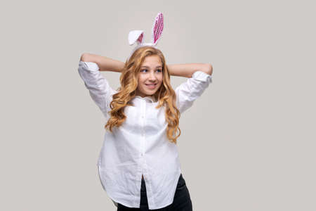 Girl in rabbit ears on her head against backdrop studio. Cheerful suffering smiling happy young. Caucasian girl In a white shirt. Easter and holidays.の写真素材