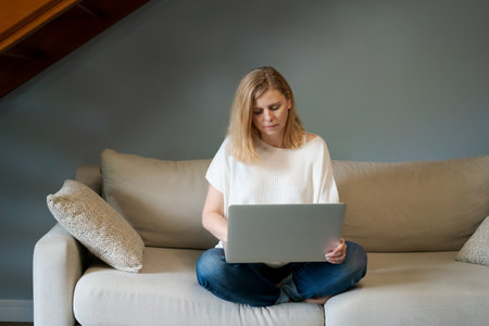 Cute adult woman working on computer. Caucasian woman doing remote work on a laptop while sitting on...