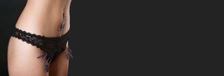 Woman has small lavender flowers sticking out from under her pants, mimicking extra hair. Laser hair removal and shaving with razor. Conceptual shot about womens issues. Proper self care on blackの写真素材