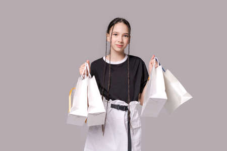 Shopping teenager girl holding shopping bags in her hands Fashion woman shopper isolated on gray...