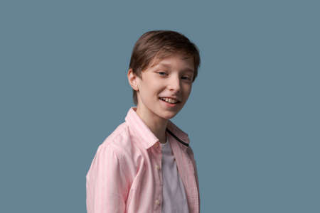 Smiling funny young man in casual white t-shirt and pink shirt posing on light wall background studio portrait. People sincere emotions lifestyle concept. Layout copy space. Holding hands, white teethの写真素材