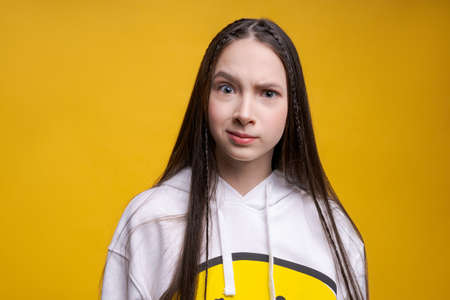 Close-up portrait smiling cute young brunette girl with long hair, wearing white sweatshirt, on a...