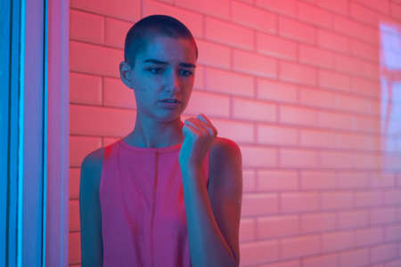 Lonely sad teenager girl student knocking on window in frustration, sad young woman with short hair,...