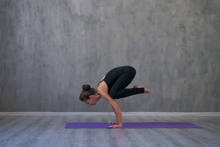 Athletic young woman practice yoga down, face down isolated on gray wall background in black...