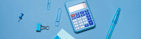 Calculator, stationery accessories on blue background with copy space. Look, school accessories for...