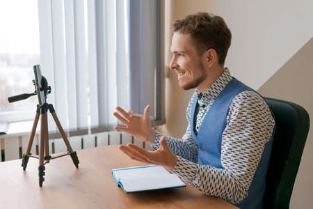 Successful caucasian student in 20s Male student focused on doing homework online in notepad and...