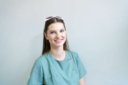 Doctor laser hair removal cosmetics in protective glasses on his head in green coat. Portrait of a beautician in her office in a modern beauty clinic. Preparation for the epilation procedureの写真素材