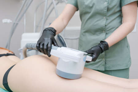 Vacuum massage apparatus. Anti-cellulite body shaping procedure. Apparatus for weight loss. Woman and doctor in medicine salon. Hardware massage in a beauty salonの写真素材