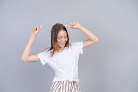 Beauty fashion and lifestyle concept. Close-up carefree beautiful young woman, dancing with her hands raised up and laughing happily with her eyes closed, standing on a gray background joyfulの写真素材