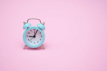 Blue alarm clock on a pink background. Copy space. Close-up. Deadline conceptの写真素材
