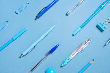 Pens pencils compasses paper clips laid out in lines all blue and background, concept for school...