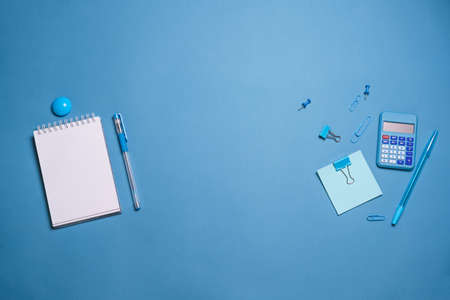 Stationery colorful supplies for writing pens pencils, on colored paper on a blue background. Back...
