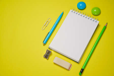 Notebook and pen on a yellow background. Top view with copy space. Stationery for school and office