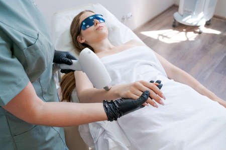 Large laser hair removal in beauty salon. Woman with hand epilation. Happy client at the procedure....