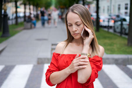 Attractive businesswoman talking on a mobile phone with a client standing on a city street during...