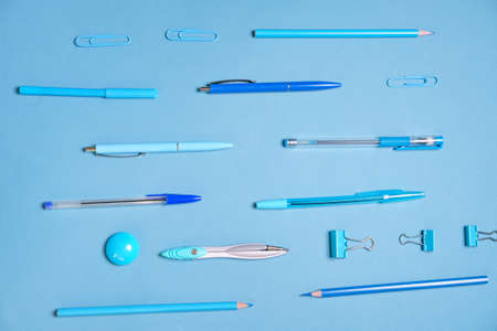 Pens pencils compasses paper clips laid out in lines all blue and background, concept for school stationery items and for businessの写真素材
