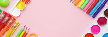 School stationery colorful paint pencils and pens on pink background in form of a frame, the concept of back to schoolの写真素材