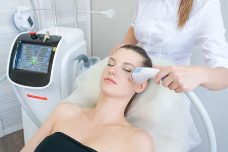 Gorgeous woman in beauty clinic receives non-surgical face lift. SMAS ultrasonic uplift. Facelift. Rejuvenation process. Spa treatment. Hardware cosmetology.の写真素材