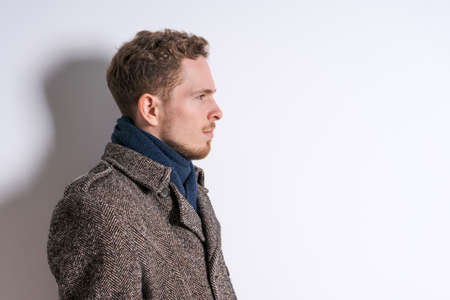 Portrait handsome bearded man in coat with scarf, male beauty, seasonal fashion. Studio shot on a...