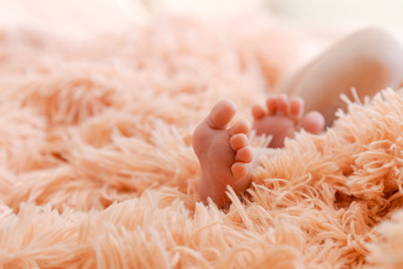 Childrens feet on fluffy pink plaid. Tiny feet newborn baby close up with copy space. Mom and her child. Happy family concept. Beautiful concept image of motherhoodの写真素材