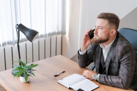 Business bearded man is talking on phone and plans to meet daily and write a business trip in a diary on the office desk. Calendar scheduling planners and agenda reminders.の写真素材