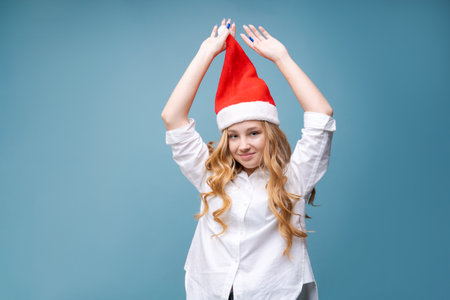 Portrait joyful pretty woman in a red Santa Claus hat is laughing, on background in the studio....