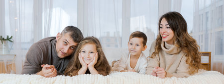 Happy family four spend time on bed hugging and smiling dad, mom and little kids bonding, loving caucasian parents, children unity, communication portraitの写真素材