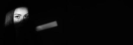 Dramatic black and white portrait beautiful lonely girl, isolated on a dark background in a studio shot, with copy spaceの写真素材