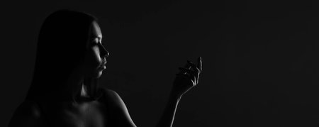 Dark female silhouette, hands and face. Artistic portrait. Required photo of the womans body. Black and white silhouette of female body art photography.の写真素材