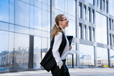 Portrait of successful business woman in stylish suit using laptop posing next to city office building. Confident female CEO smiling. Successful Diverse Business Manager.の写真素材