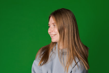 Dreamy woman in gray cozy sweatshirt. Front view interested girl isolated on green background. Happy...