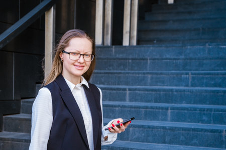 Successful businesswoman talking on mobile phone while walking outdoors near the business center. Business woman in a suit and glasses.の写真素材