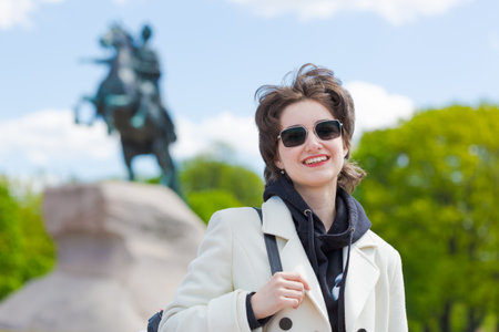 Portrait young european tourist in sunglasses, wearing white coat and black sweatshirt with a black...