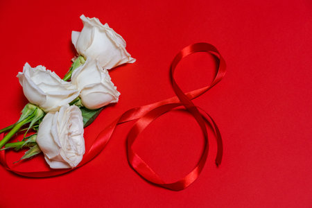 Greeting card for womens day March 8, number eight from red ribbons, bouquet of roses on a colored backgroundの写真素材