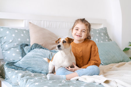Happy mom and daughter play with their adorable wired Jack Russell Terrier puppy at home. Loving family with a puppy in the bedroom. Background, close-up, copy space.の写真素材