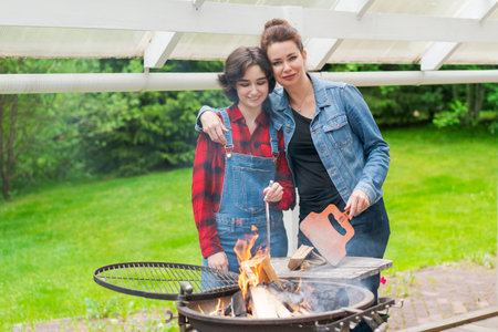 Barbeque party in garden with mom and her daughter at the grill in a country houseの写真素材