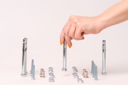 screws and nuts and bolts, stand on a light background, the hand moves the bolt construction conceptの写真素材