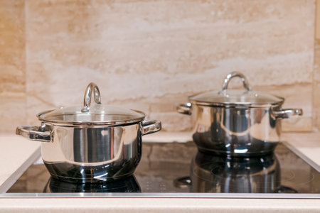 two chrome pans with stota lids on an electric touch plate. close-up. home cooking concept