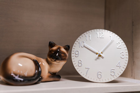 white clock and cat figurine stand on a shelf, home decor