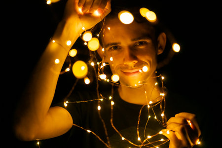 young guy at night holding glowing garlands in his hands, selective focusの写真素材