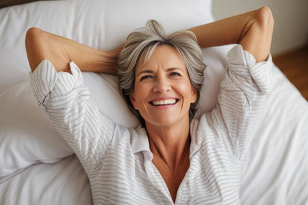 happy mature woman in the morning in bed at home, good carefree morning.の素材