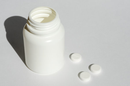 White medical pills and tablets spilling out drug bottle. with copy space.