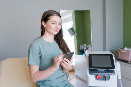 woman is sitting in room with tan counter and tan wall. She is holding cell phone and she is textingの写真素材