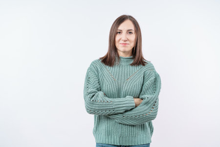 A woman is wearing a green sweater and is standing with her arms crossed. She has a serious expression on her faceの写真素材